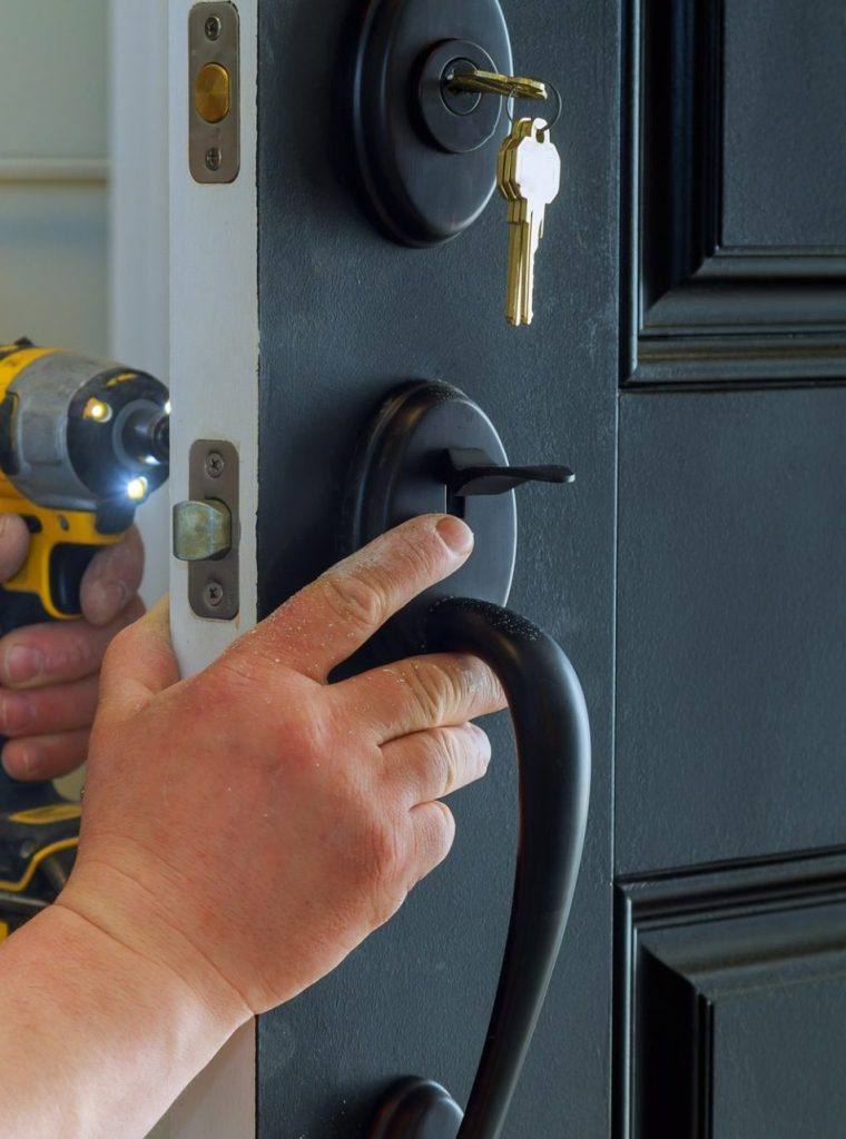 man installing lock on door with a drill